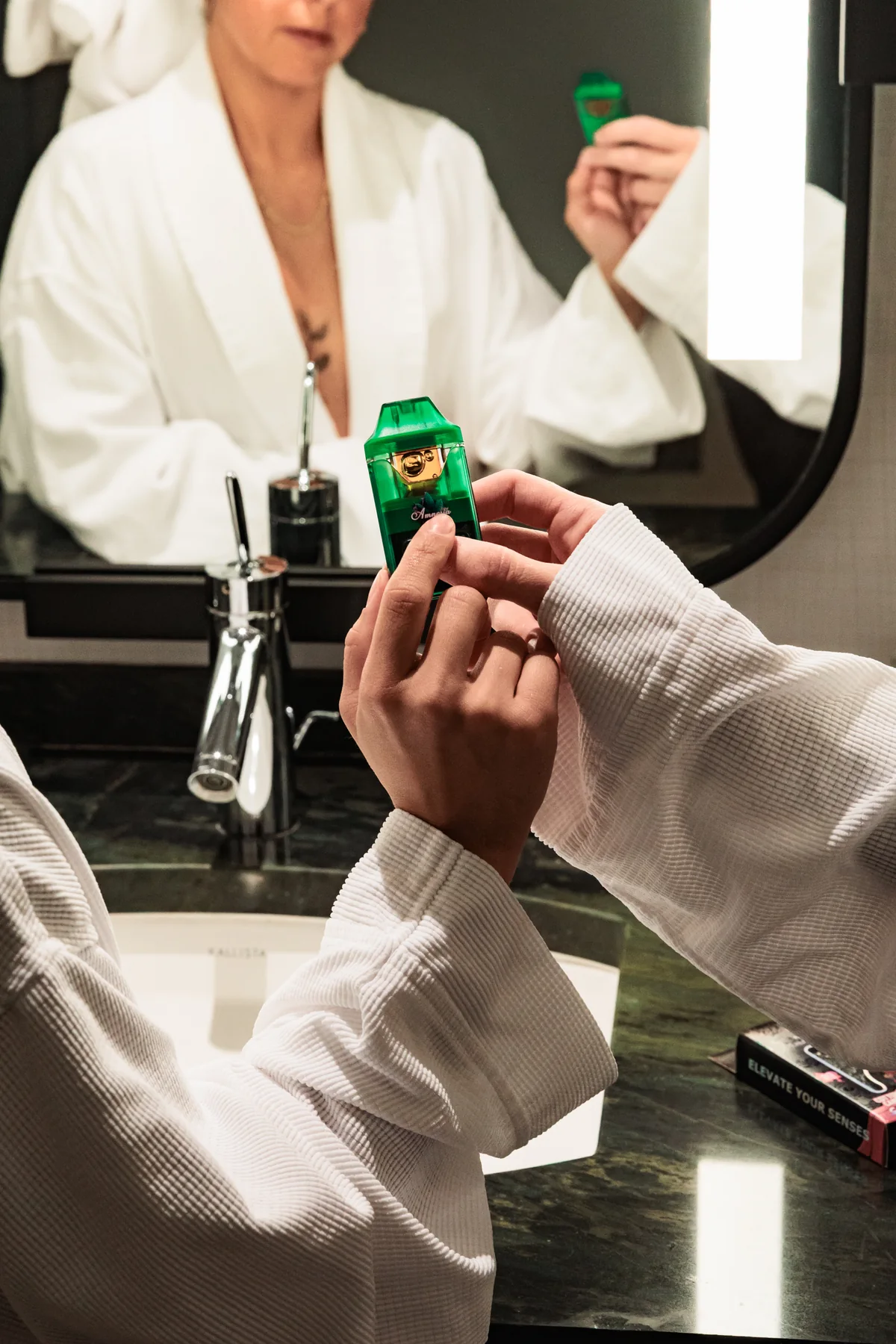 Green Amnesia vape held in front of a hotel mirror during the brand photoshoot